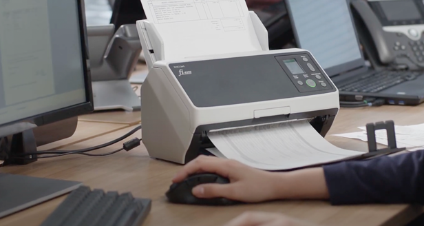 close up of a person's hand using a computer mouse with a Ricoh fi scanner on the desk